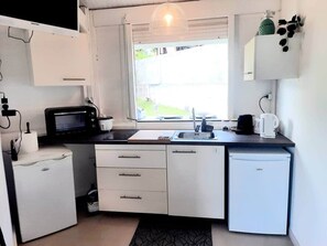 A compact kitchen with a microwave, sink, and small refrigerator. - Cocoon Cap (Sainte-Anne)