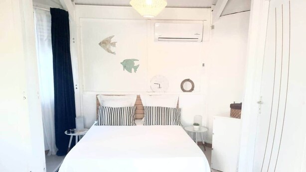 Un dormitorio con cama, mesita de noche, una pequeña mesa y un armario.