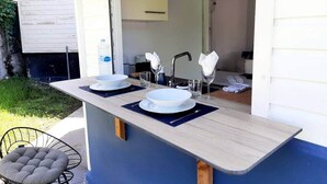 Una cocina con barra, dos tazones blancos, vasos y un reloj en la pared.