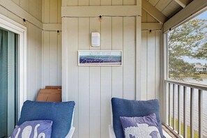 A porch with two blue cushioned chairs, a welcome sign, and a window overlooking a body of water. - Lakefront house w/screened-in patio, pool, close to beach & golf (Pawleys Island)