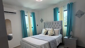 Quarto com cama, mesa de cabeceira e aparelho de ar condicionado.
