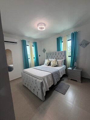 A bedroom with a bed, nightstand, and air conditioning unit.