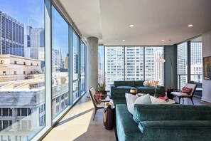 Una sala de estar moderna con ventanas amplias, un sofá verde, una silla y una lámpara de pie.