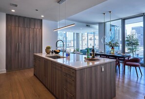 Una cocina moderna con una isla grande, armarios de madera y vistas a la ciudad a través de amplias ventanas.