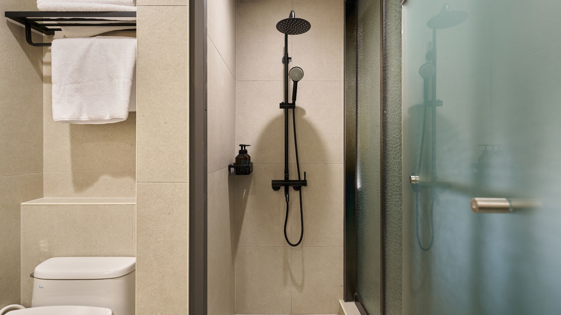 A bathroom with a shower, toilet, and towel rack.