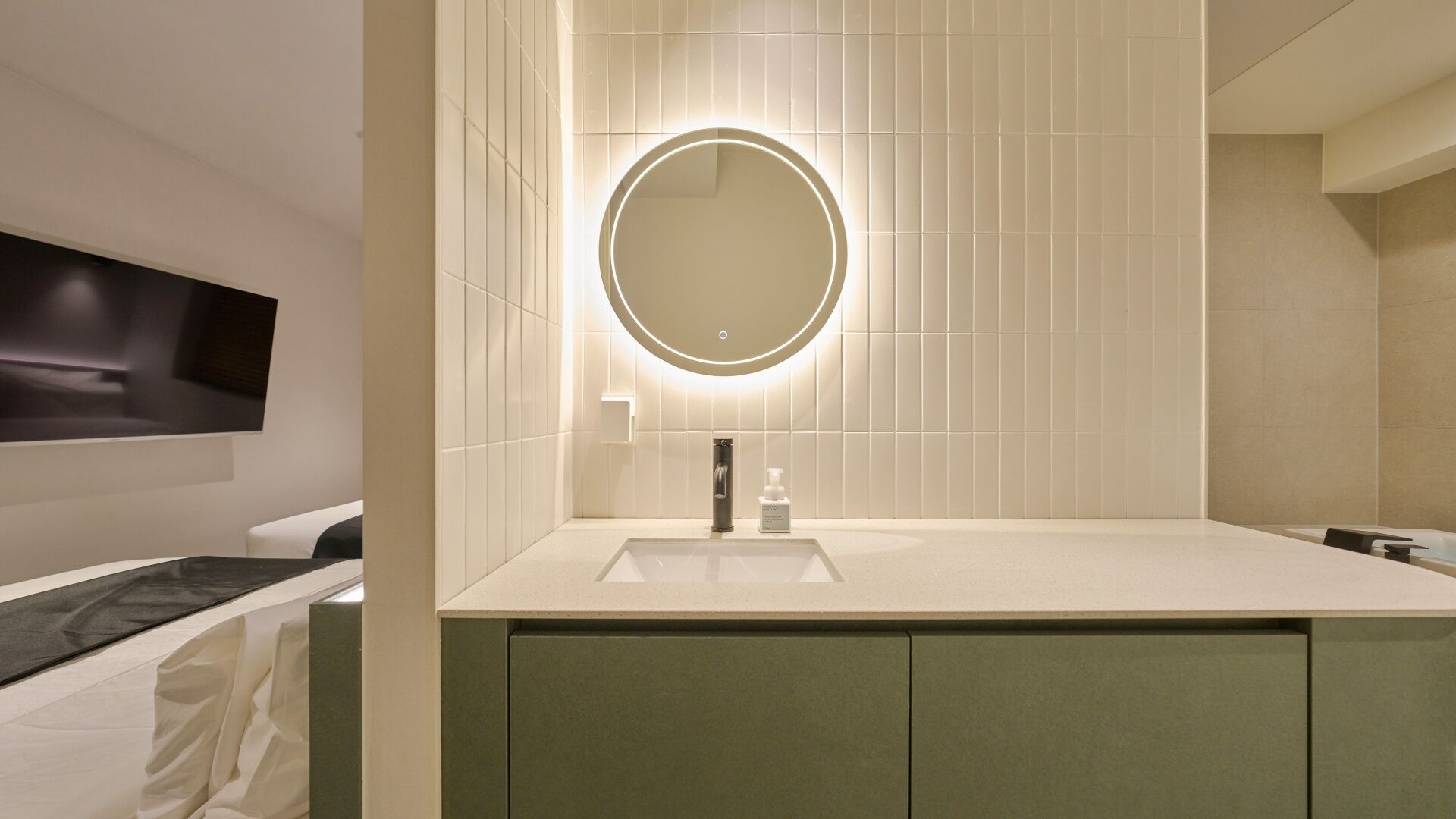 A modern bathroom with a round mirror, a sink, and a towel rack.