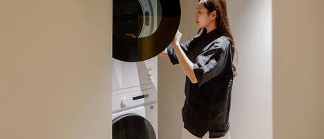 A person standing in a room with a washing machine and dryer in the background.