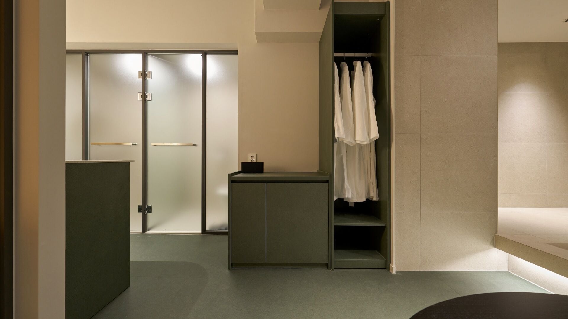 A modern bathroom with a shower, a towel rack, and a small cabinet.