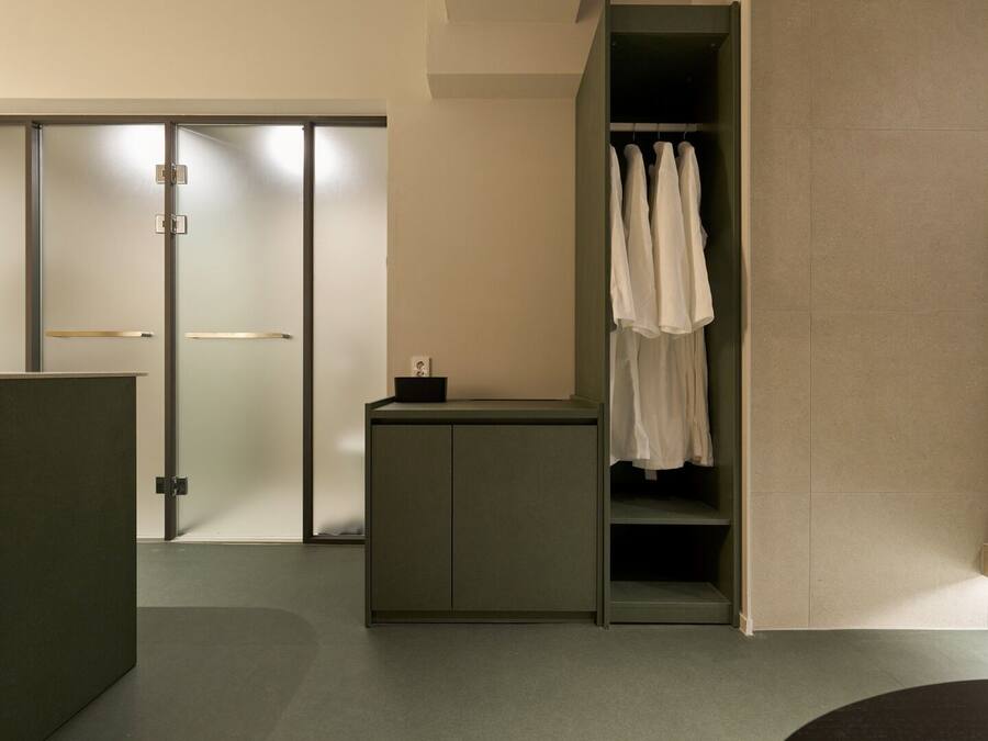 A modern bathroom with a shower, a towel rack, and a small cabinet.