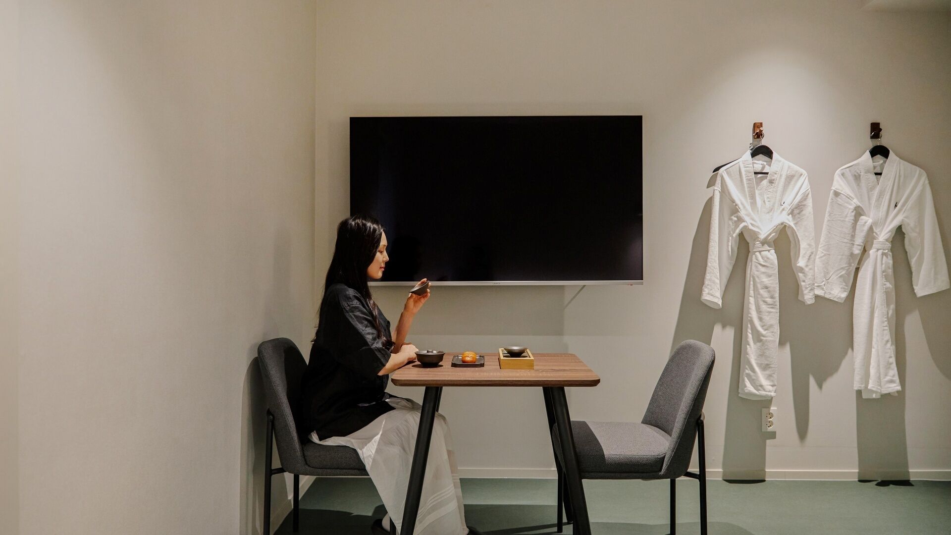 Una habitación con televisión, una mesa con cuencos y dos sillas.