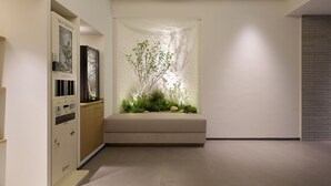 Um interior moderno com um quiosque de autoatendimento, um banco e um vaso vertical com plantas.