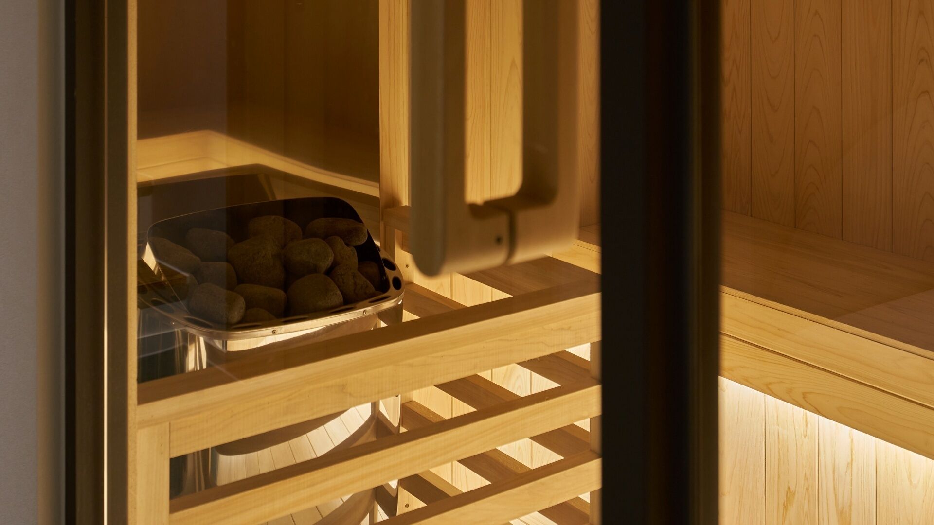 Un sauna avec un banc en bois et un récipient en verre contenant des pierres.