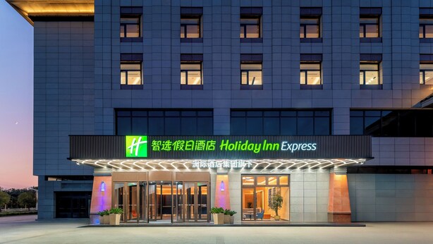 A Holiday Inn Express hotel with a modern facade, large windows, and a well-lit entrance. - Holiday Inn Express Luoyang Longmen (Luoyang)