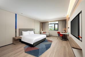 Ein modernes Hotelzimmer mit einem großen Bett, einem Schreibtisch und einem Fernseher.