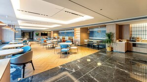 A modern hotel lobby with multiple seating areas, a reception desk, and a mix of wooden and carpeted flooring. - Holiday Inn Express Luoyang Longmen (Luoyang)