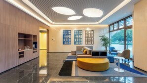 A modern lobby with a curved sofa, a small table, and a seating area with chairs. - Holiday Inn Express Luoyang Longmen (Luoyang)