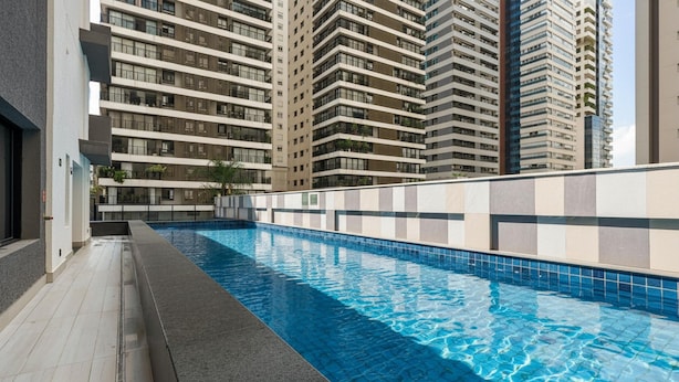 A swimming pool with a tiled edge, surrounded by high-rise residential buildings. - Apto in Condo w/ Pool in Setor Marista Liu2306 (Goiânia)