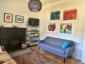 Ein Wohnzimmer mit Kamin, Sofa und Kunstwerken an der Wand.