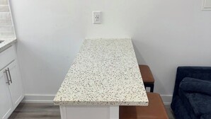 A kitchen with a white countertop, a bench, and a dark blue sofa. - 2-bed apartment in vibrant South Phila neighborhood walking distance to stadiums (Philadelphia)