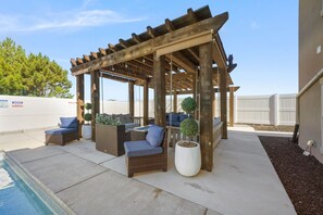 Een overdekt terras met rieten meubilair en plantenbakken.