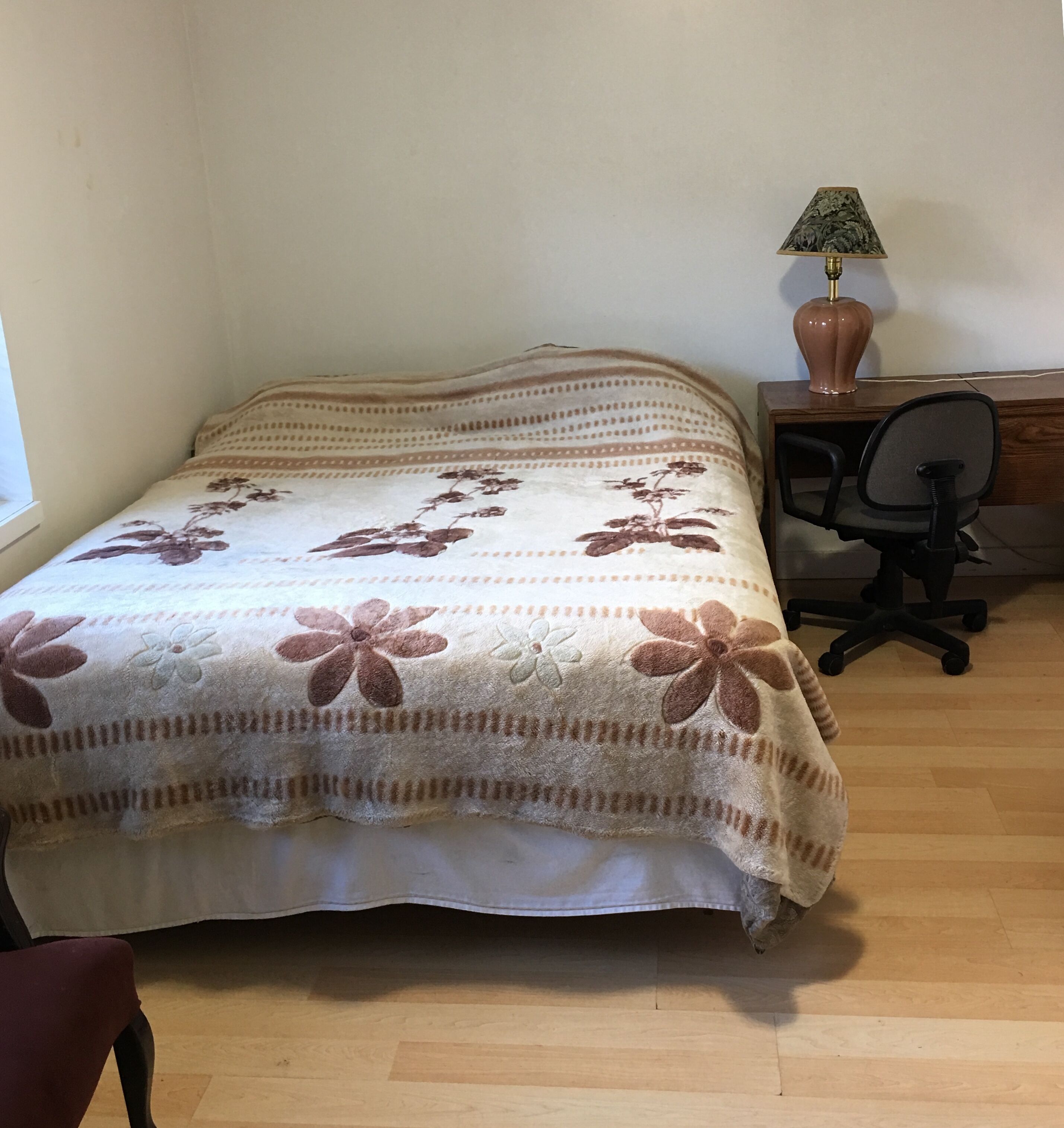 Un dormitorio con cama, escritorio, silla y lámpara.