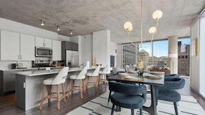 Une cuisine moderne dotée d’un îlot central, de tabourets de bar et d’un coin repas avec une table dressée pour quatre personnes.