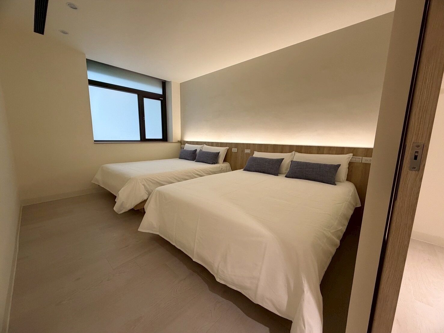 A hotel room with two beds, a window, and a wooden headboard.