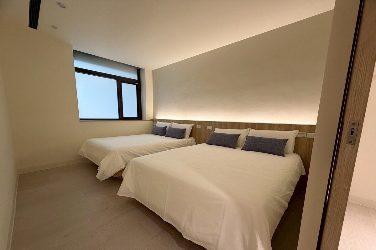 A hotel room with two beds, a window, and a wooden headboard.