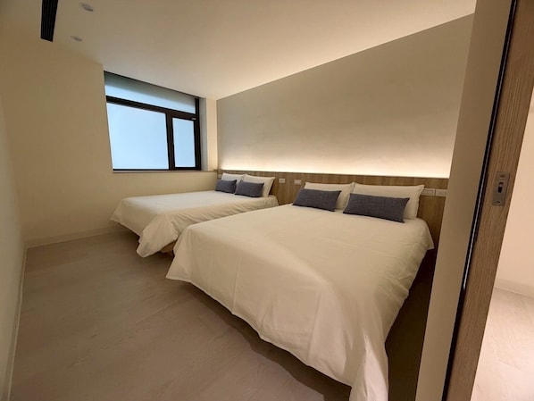 A hotel room with two beds, a window, and a wooden headboard. - Phoenix Landing (Tainan)