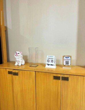 A wooden cabinet with a white cat figurine, a clear glass container, a date sign, and a Wi-Fi sign. - MOA Staycation - MOA Homestay (Pasay City)