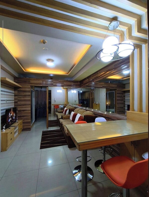 A modern dining area with a long wooden table, red chairs, and a central light fixture. - MOA Staycation - MOA Homestay (Pasay City)