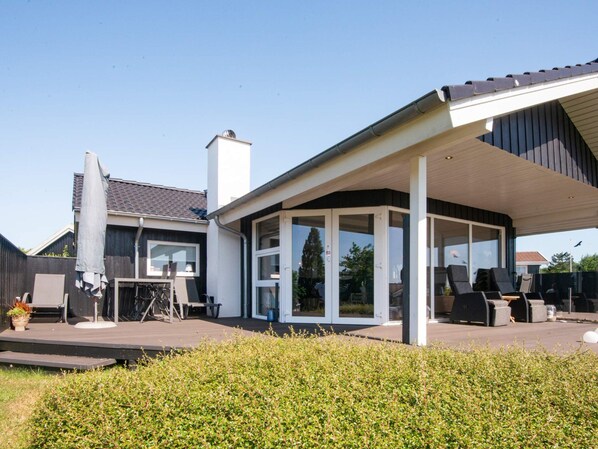 A modern house with a covered patio, a visible chimney, and a fenced backyard. - 4 Star Holiday Home in Hejls (Hejls)