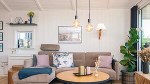 A living room with a sofa, a round coffee table, pendant lights, a fireplace, and a window with a view. - 4 Star Holiday Home in Hejls (Hejls)