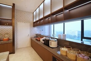 Uma cozinha moderna com fogão embutido, máquina de café e janela com vista para a cidade.