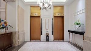 A hotel lobby with a chandelier, two elevators, a reception desk, and a marble floor. - Vienna International Hotel Guangzhou Baiyun International Airport Branch - Free Shuttle Bus to Guangzhou Baiyun International Airport & Free Deliver Service to Canton Fair Complex During Canton Fair Period (Guangzhou)