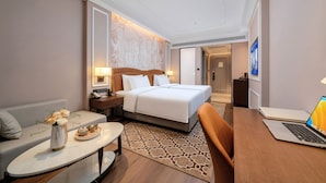 A hotel room with a bed, bedside table, lamp, laptop, and a small table with a vase of flowers. - Vienna International Hotel Guangzhou Baiyun International Airport Branch - Free Shuttle Bus to Guangzhou Baiyun International Airport & Free Deliver Service to Canton Fair Complex During Canton Fair Period (Guangzhou)