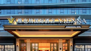 The Vienna International Hotel entrance with a modern facade, large glass doors, and a sign indicating it is an international hotel. - Vienna International Hotel Guangzhou Baiyun International Airport Branch - Free Shuttle Bus to Guangzhou Baiyun International Airport & Free Deliver Service to Canton Fair Complex During Canton Fair Period (Guangzhou)