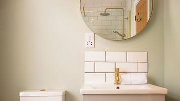 A bathroom with a toilet, sink, mirror, and a shower area.