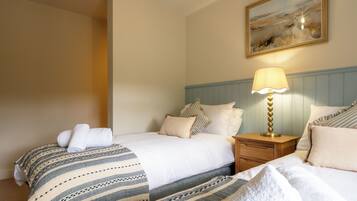 Habitación de hotel con dos camas, una mesita de noche con lámpara y un cuadro en la pared.