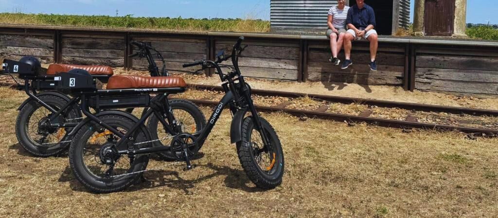 A bicycle parked on a dirt path with a wooden structure in the background.