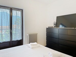 A bedroom with a bed, a dresser, a radiator, and a television. - Francesco by Interhome (Domaso)