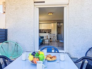 A dining area with a table set for two, a bowl of fruit, and a plate of croissants. - Croix du Sud by Interhome (Canet-Plage)