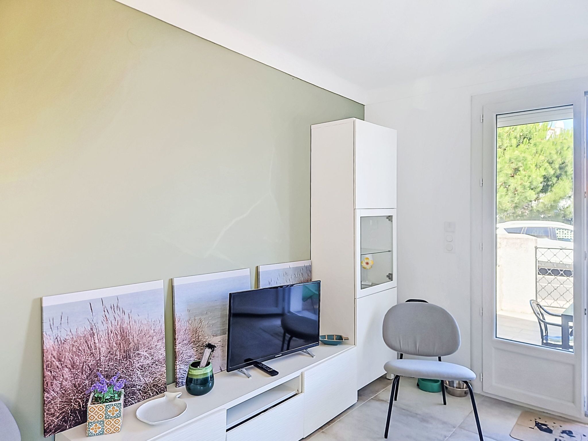 A modern living room with a flat-screen TV, a sofa, a chair, and a dining table.