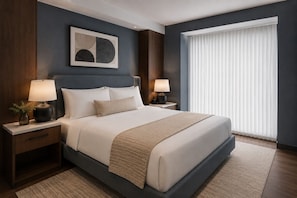 A modern hotel room with a large bed, two bedside tables with lamps, a framed abstract artwork, and a large window with blinds. - The Quarry Hotel (Toronto)