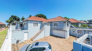 A residential area with houses featuring red-tiled roofs, a central staircase, and a car parked in the driveway. - Romsey Holiday Breeze (Durban North)