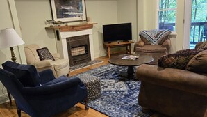 A living room with a fireplace, a television, a sofa, a chair, and a lamp. - Two bedroom  in United States of America, Glenville (Glenville)