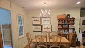 A dining room with a wooden table and chairs, a chandelier, framed fish artwork, and a bookshelf with various items. - Two bedroom  in United States of America, Glenville (Glenville)