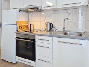 A modern kitchen with white cabinets, a stainless steel kettle, a built-in oven, and a sink with a faucet. - Apartment Emma by Interhome (Krk/Malinska)