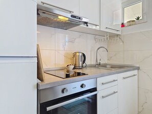 Eine moderne Küche mit einem eingebauten Backofen, einem Edelstahl-Wasserkocher und einem Spülbecken.