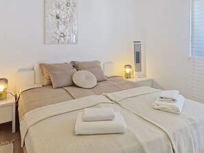 Ein ordentlich eingerichtetes Schlafzimmer mit einem Bett, Kissen, einer Nachttischlampe und einem Wandheizkörper.